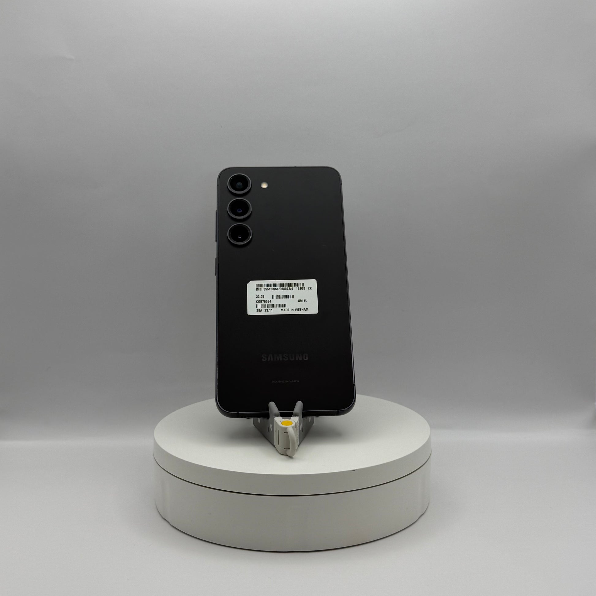 Samsung Galaxy S23 128GB Phantom Black on a turntable stand, back view
