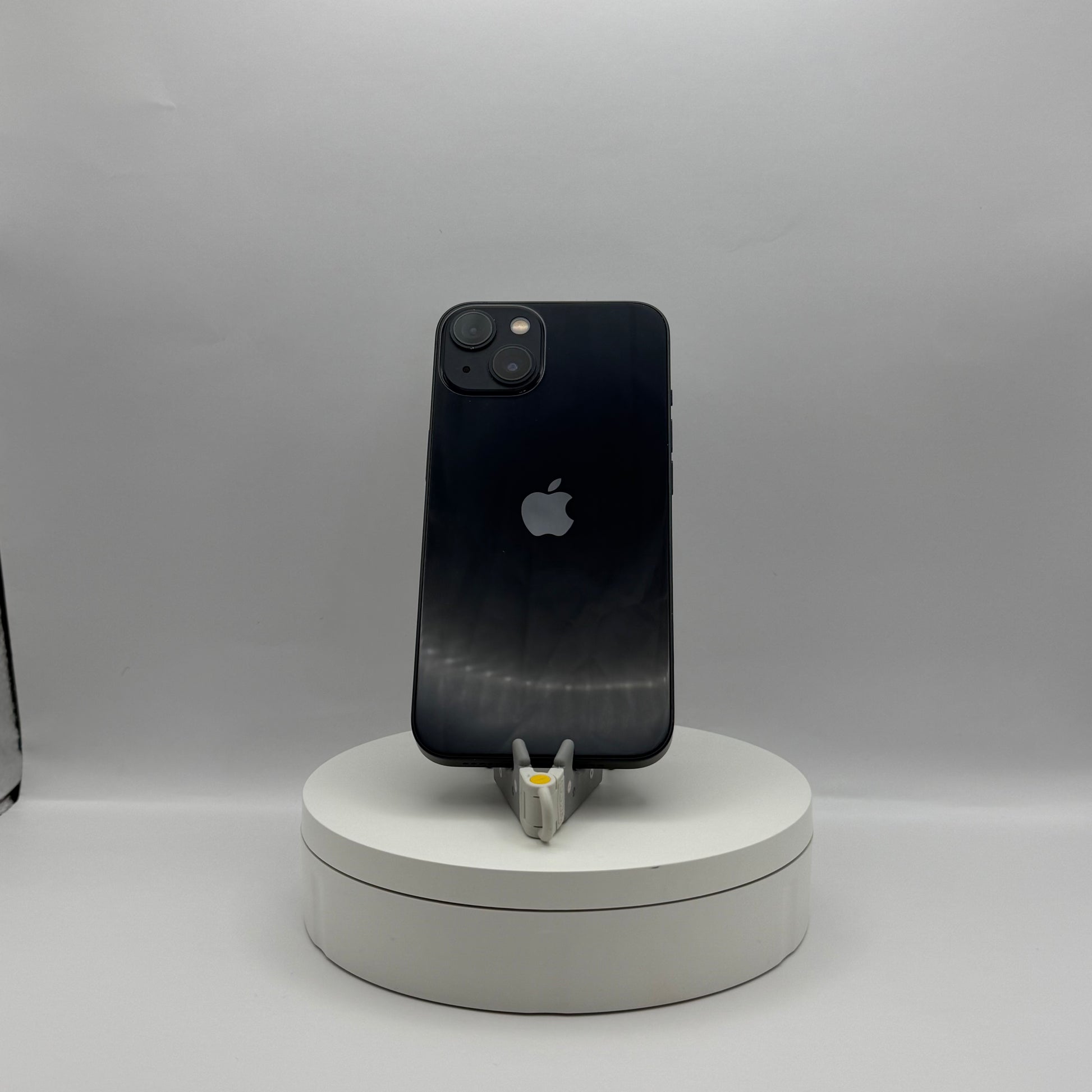 iPhone 13 128GB Midnight on a turntable stand, back view